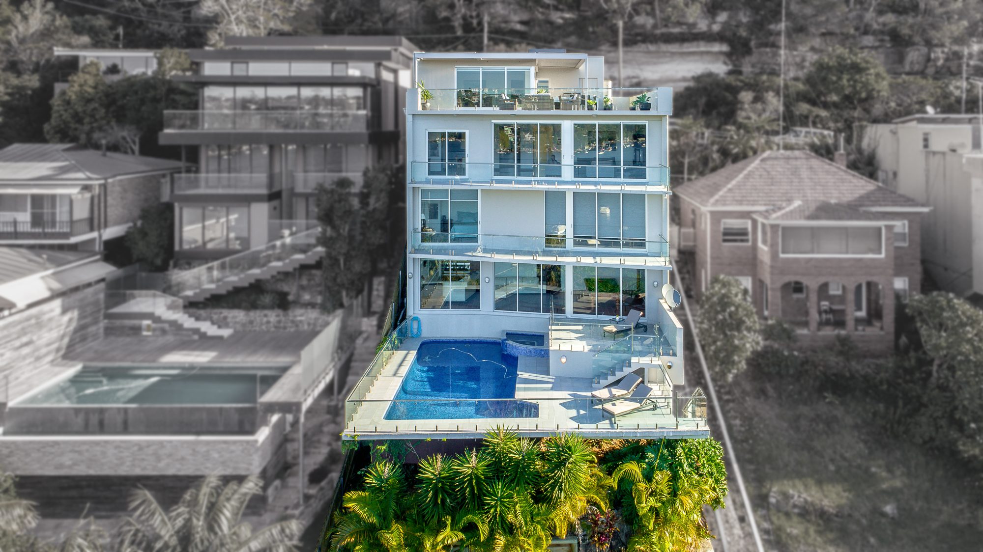 Drone photo of a waterfront home with infinity pool by UberRE