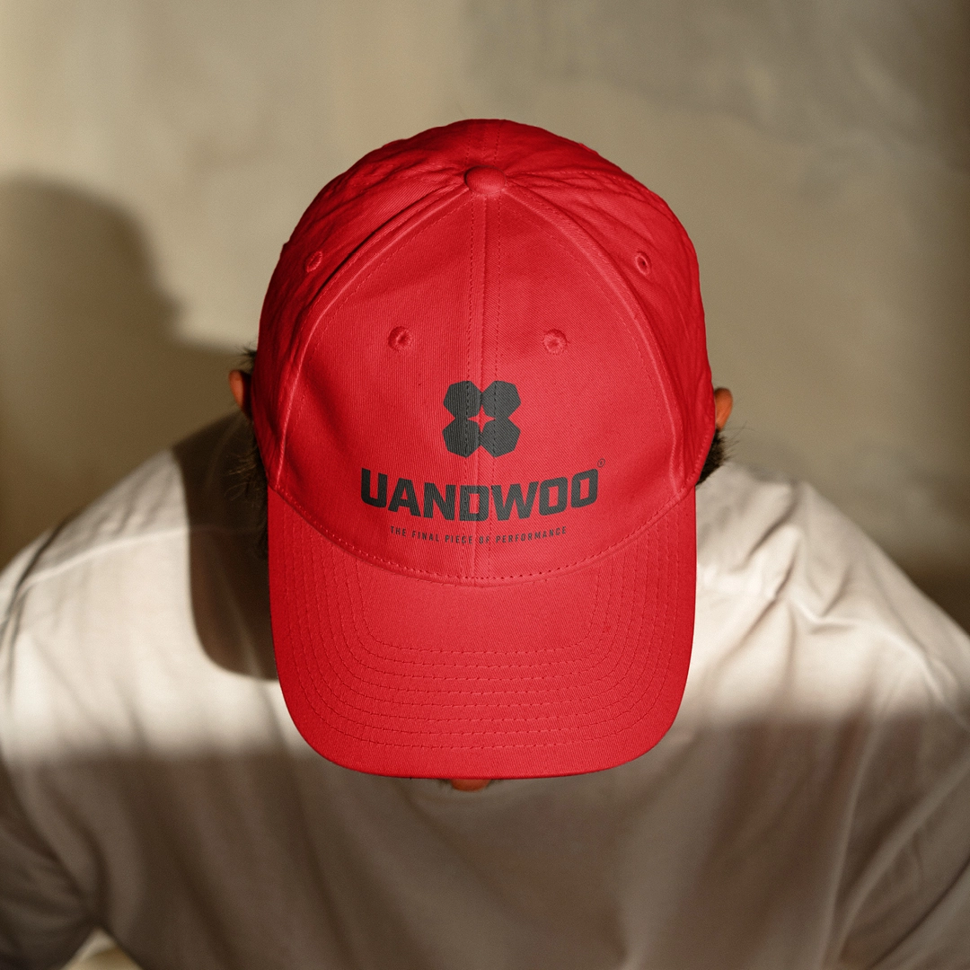 Ein Mann trägt eine rote UNANDWOO Cap mit einem schwarzen Logo
