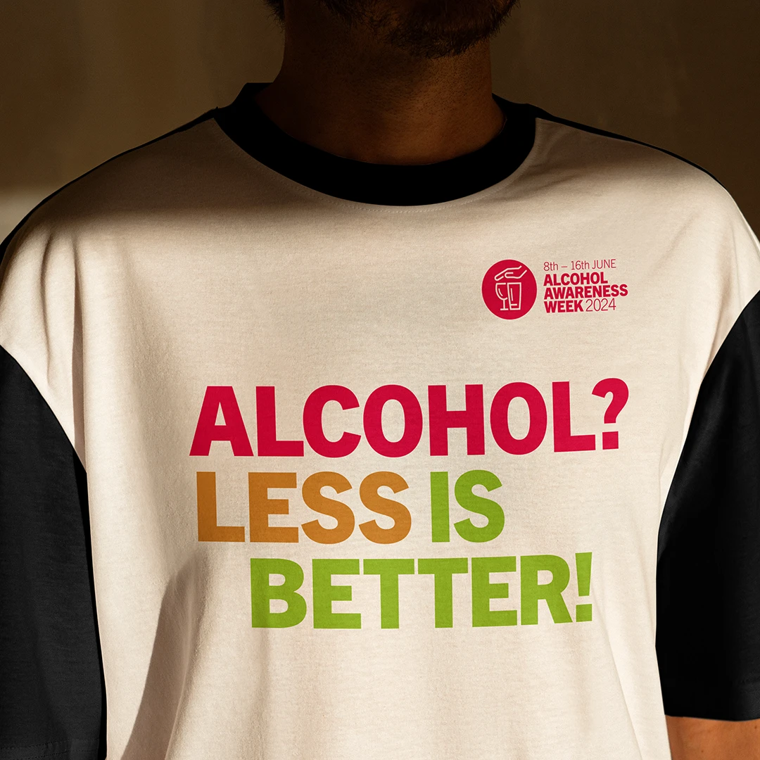Person, die ein T-Shirt mit dem Slogan „ALKOHOL? WENIGER IST BESSER!“ und das Logo der Aktionswoche Alkohol