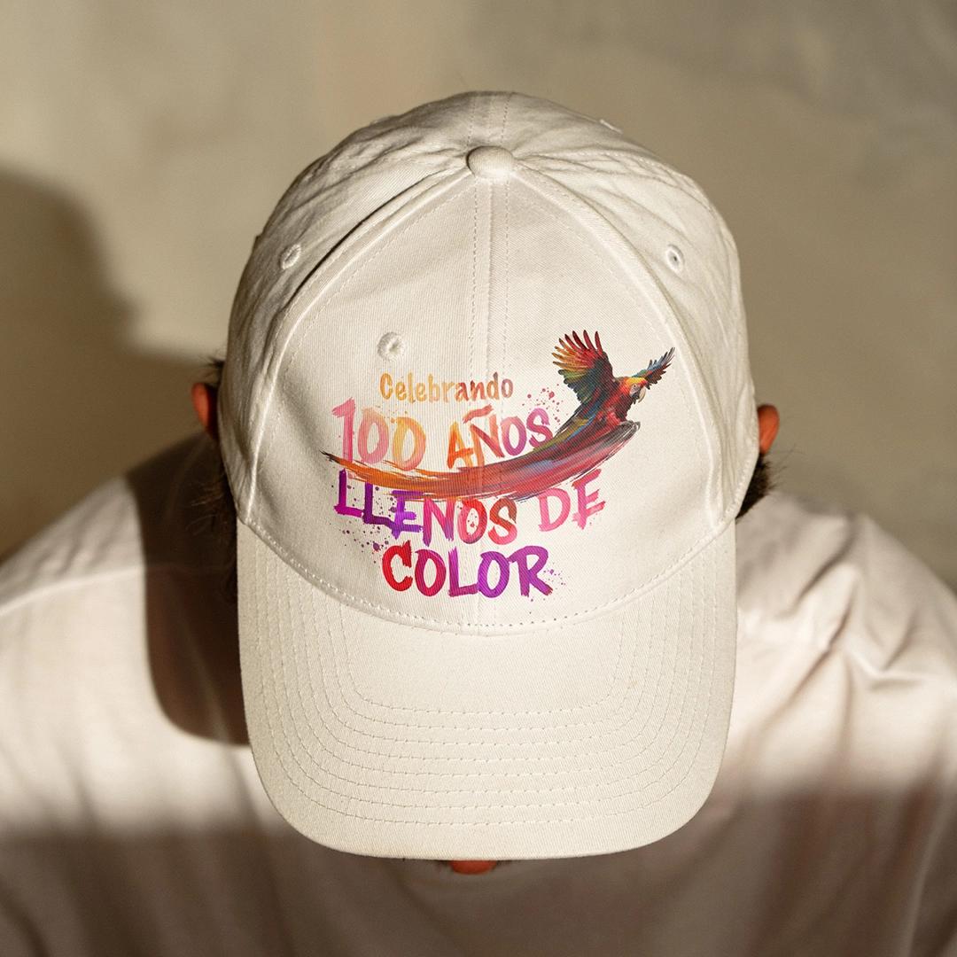 Ein Mann mit weißem Hut mit dem Key Visual „100 Colorful Years“ auf Spanisch 