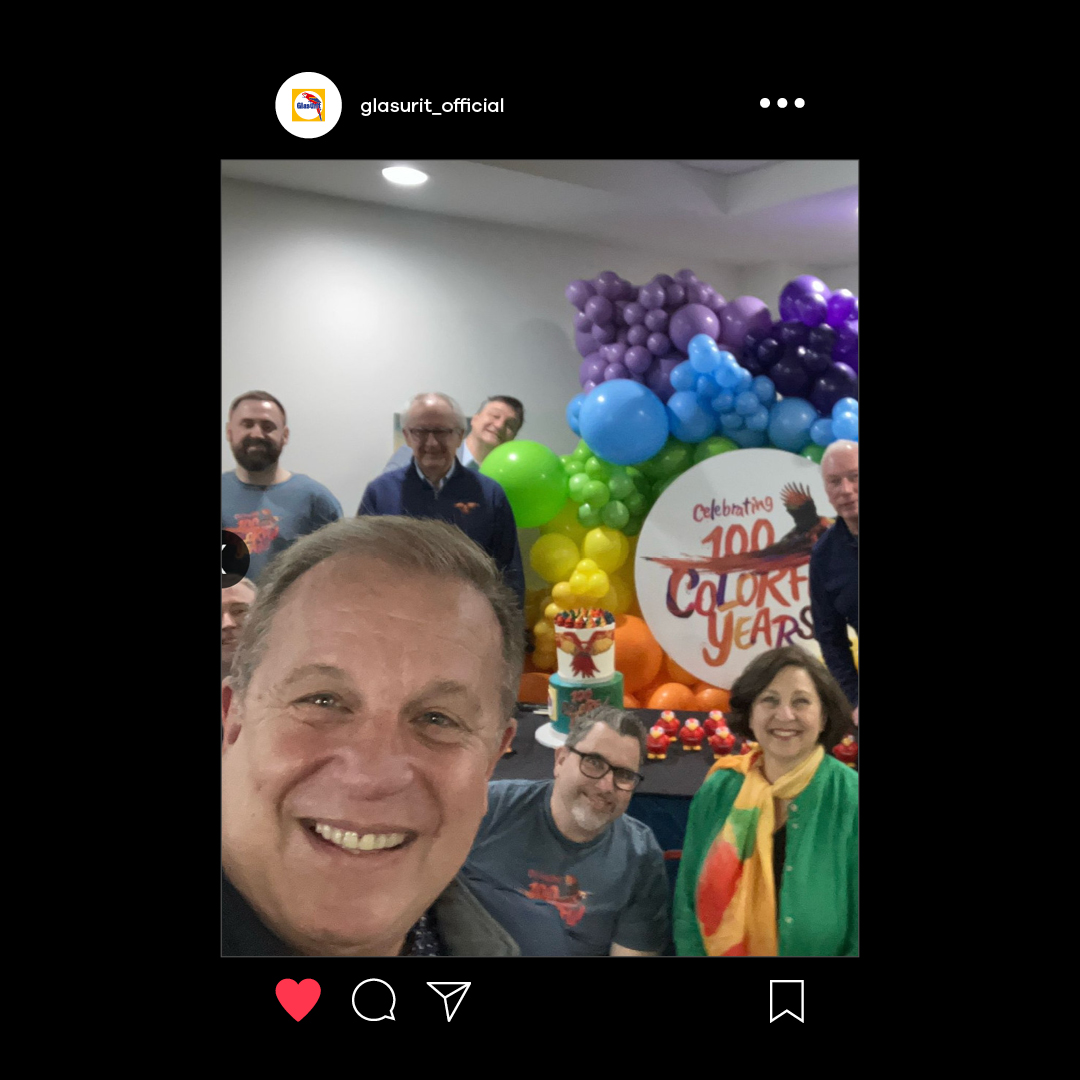 Ein Gruppen-Selfie vor bunten Luftballons und dem Key Visual der Kampagne