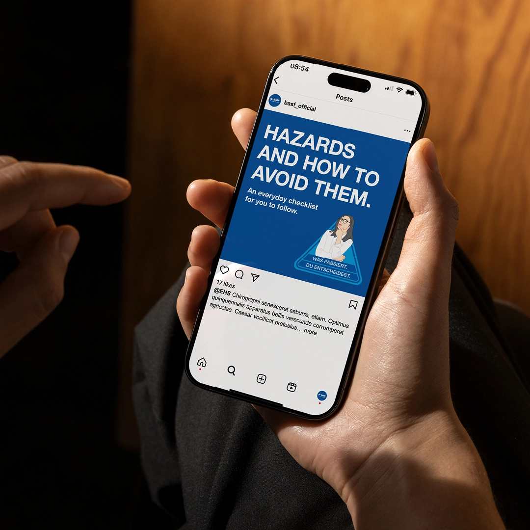 Person hält ein Smartphone mit einem BASF-Social Media-Post mit dem Titel „Hazards and how to avoid them“ und einer Sicherheits-Checkliste