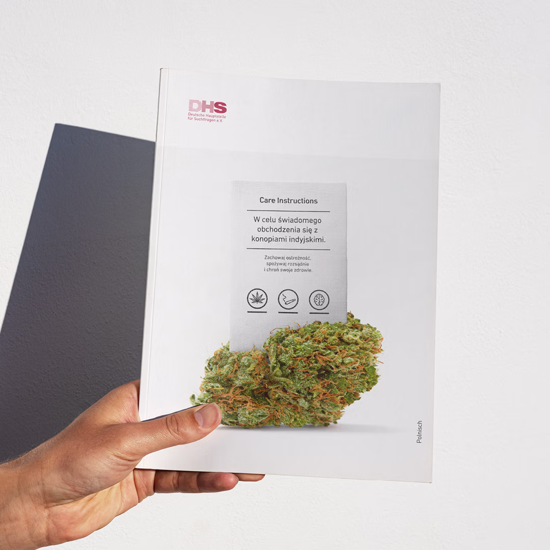 Eine Frau, die den DHS-Flyer „Vorsicht im Umgang mit Cannabis" in der Hand hält.