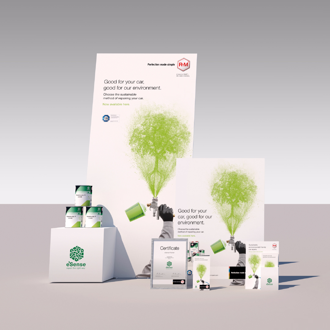 Plakate, Dosen und Zertifikate mit grünem Baum aus Farbsprühnebel, Slogan 'Good for your car, good for our environment' und R-M Logo, präsentiert auf weißem Podest.