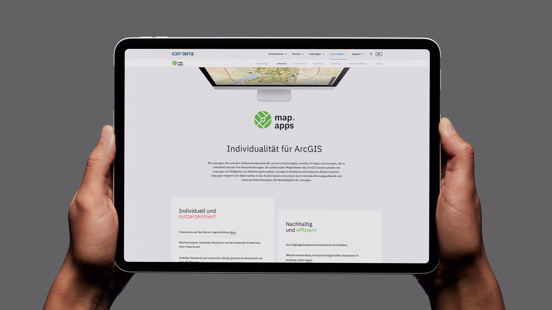 Tablet in zwei Händen gehalten zeigt Webseite von 'con terra' mit Text und zwei hervorgehobenen Abschnitten.