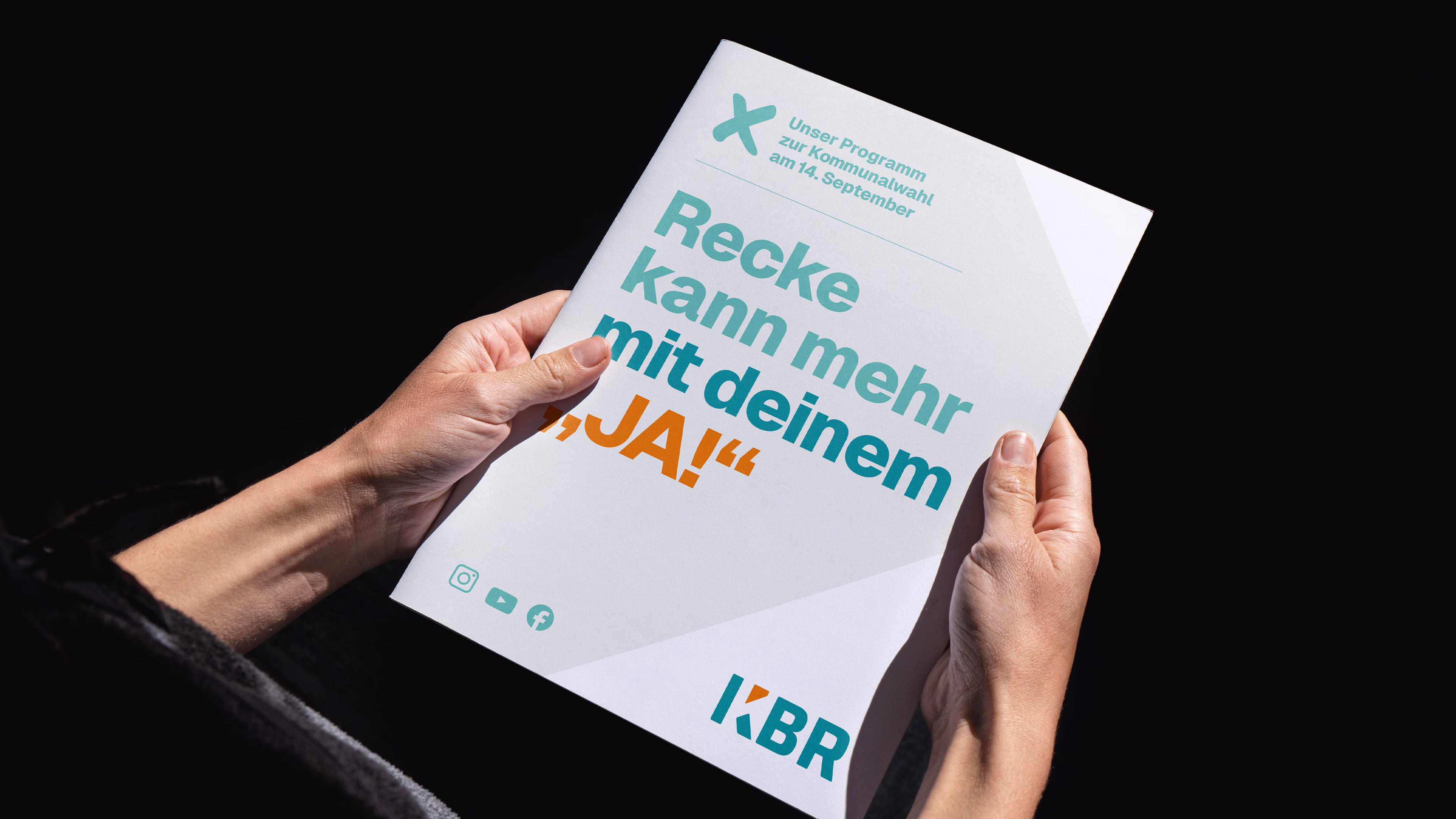 Eine Person, die das KBR-Wahlprogramm mit dem Wahlslogan „Recke kann mehr mit deinem ‚Ja!“ hält