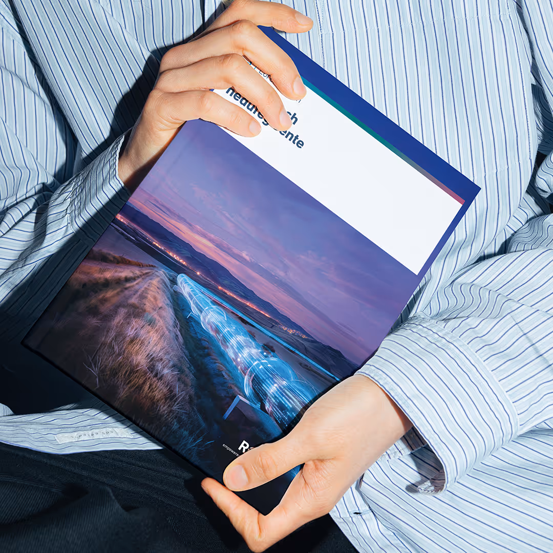 Person in einem gestreiften Hemd, die eine Broschüre mit einem digitalen Pipeline-Bild auf dem Cover hält.