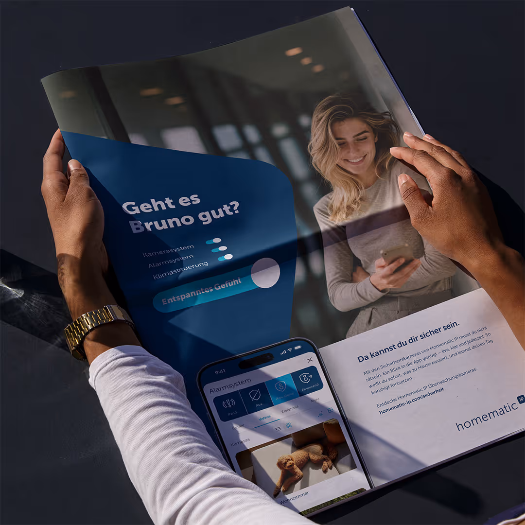 Person reading a magazine showing a smiling woman using a smartphone, with text in German about security systems and a smartphone screen displaying a home alarm app with a dog photo.