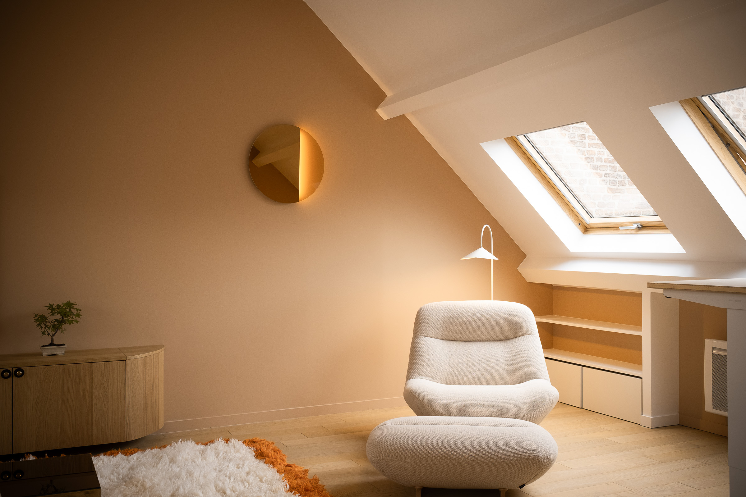 Meuble en bois clair avec étagères ouvertes, armoires fermées, et un vase avec bouquet de fleurs colorées devant un mur bleu vif.