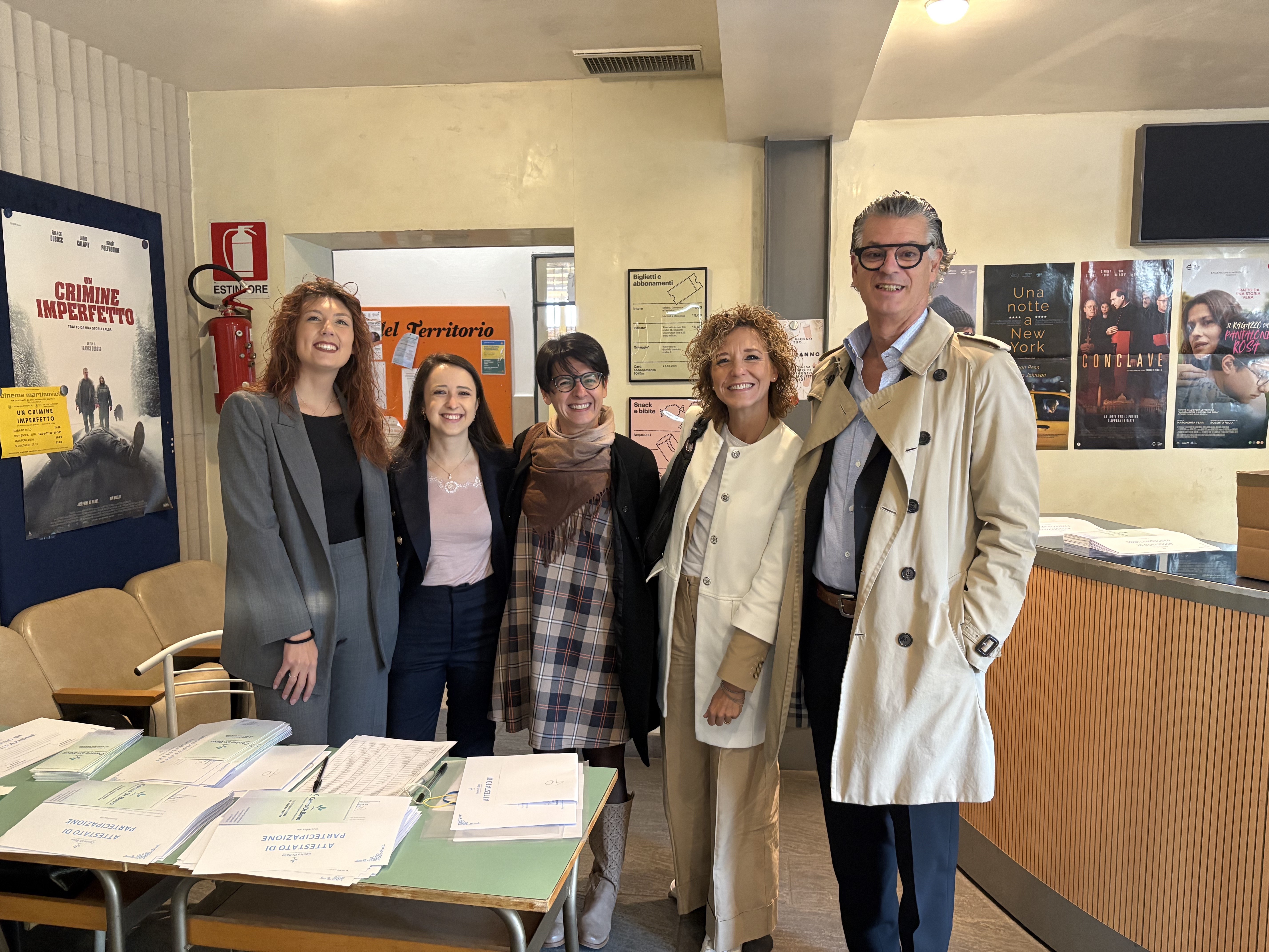 Team multidisciplinare in dialogo con famiglie e individui seduti attorno a un tavolo, in uno spazio caldo e professionale.