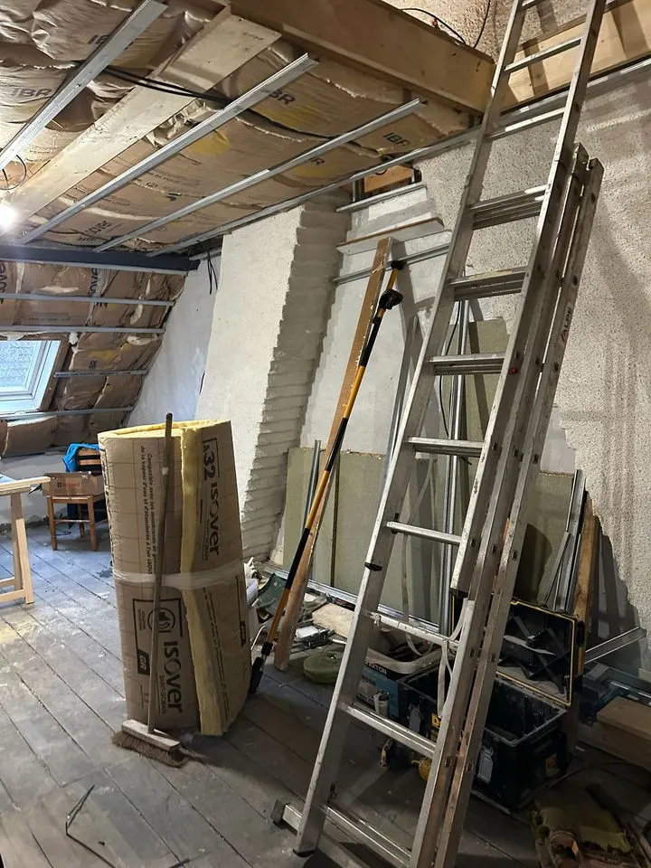 Les combles pendant les travaux : isolant, échelles et charpente à nu.