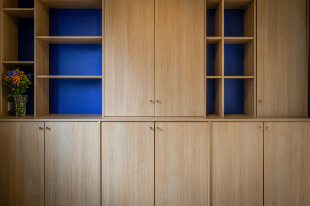 Meuble sur mesure en chêne clair avec rangements fermés et niches bleu profond.