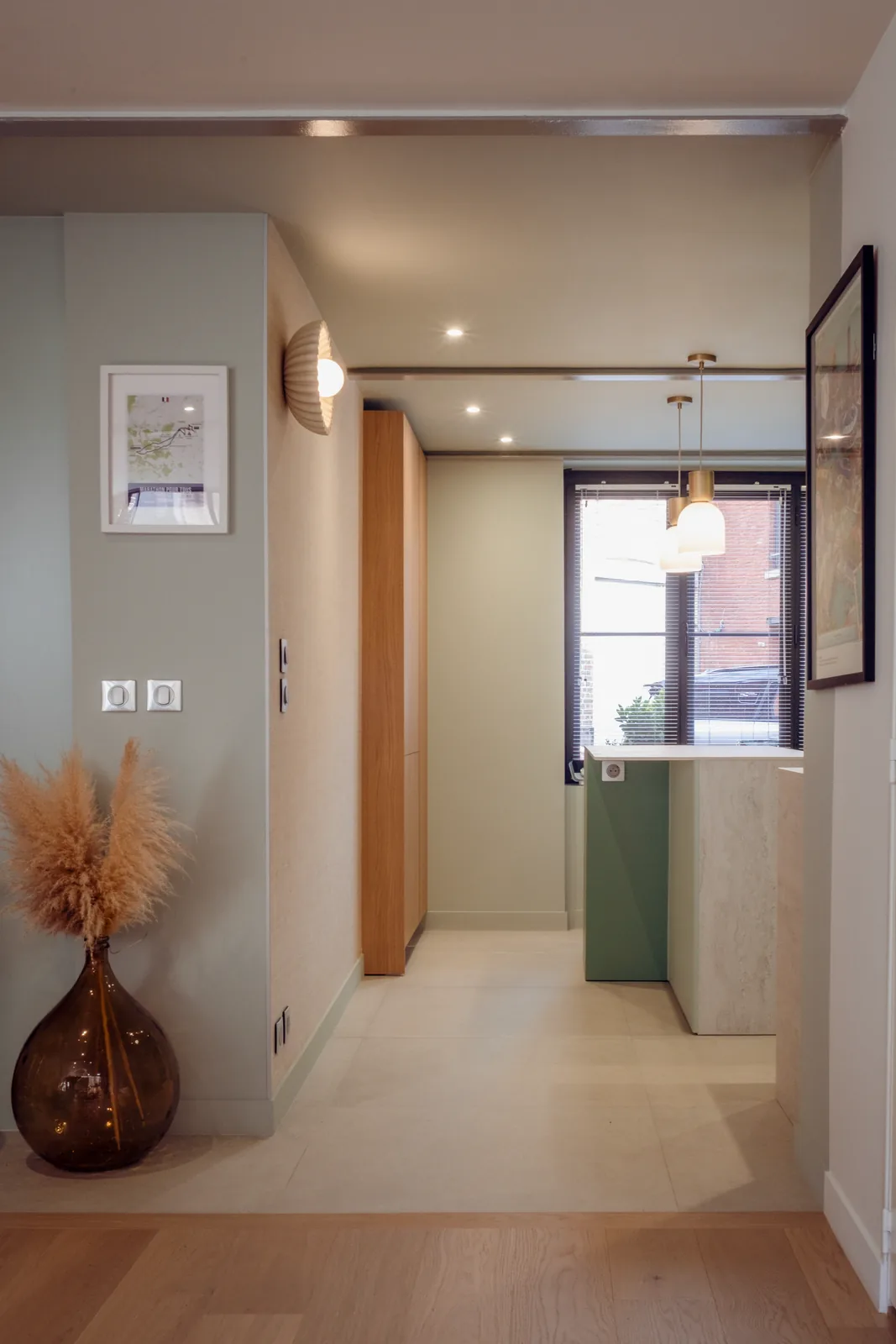 Vue depuis l’entrée vers une cuisine aux façades vertes.