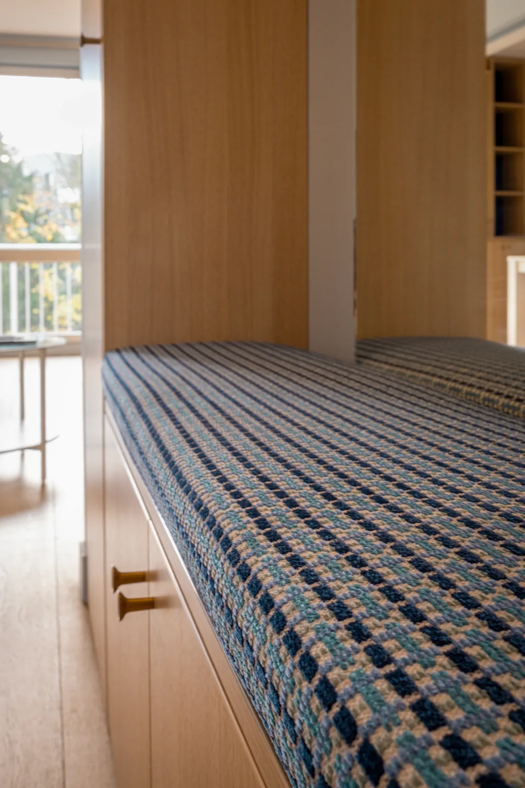Assise à motifs de la banquette intégrée, éclairée par une fenêtre.