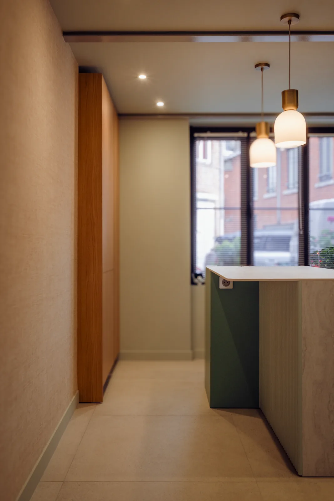 Couloir éclairé par des suspensions, menant à la cuisine verte.