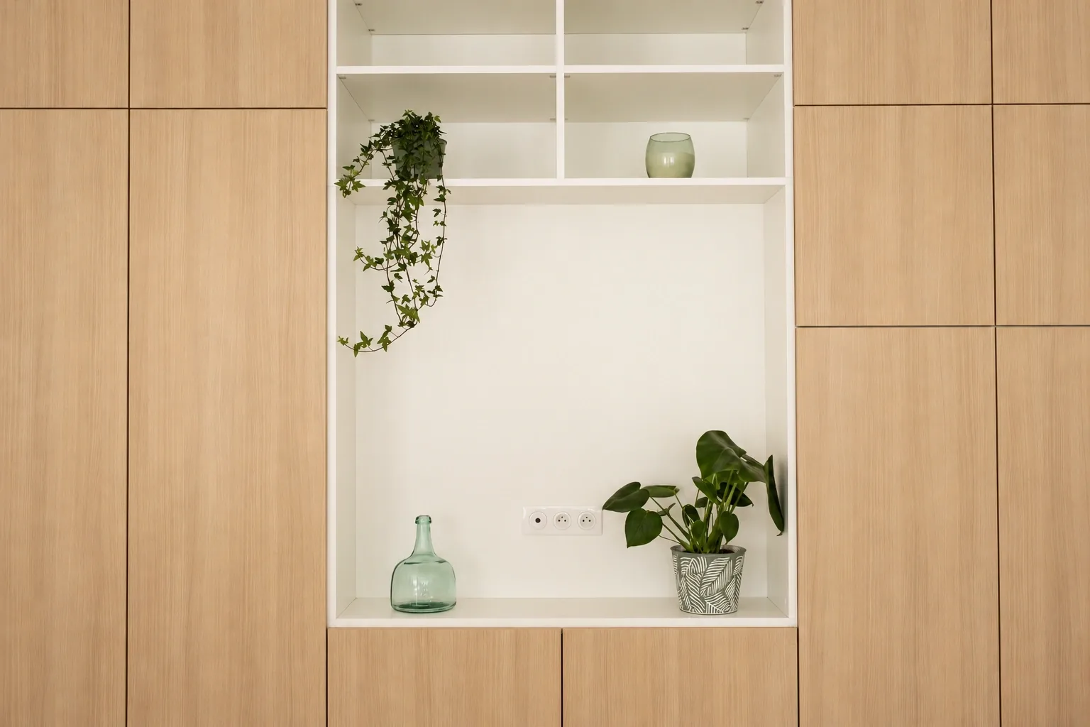 Vue frontale du meuble de salon en bois clair, avec niche blanche centrale et étagères ouvertes.