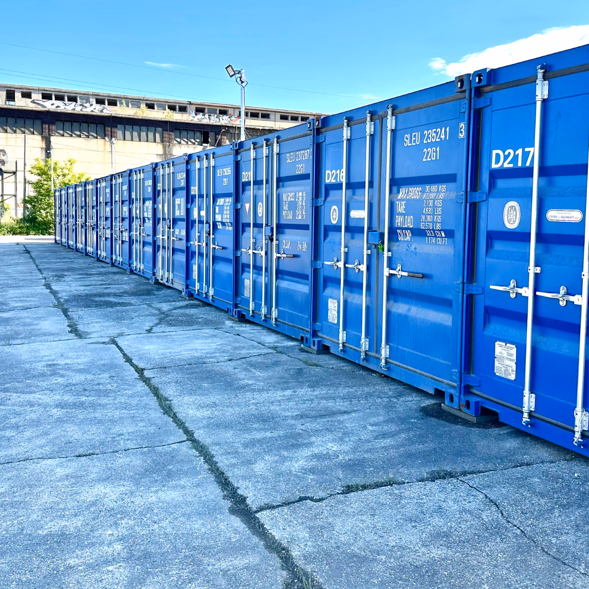 Blaue Lagercontainer in Reihe auf betoniertem Grund