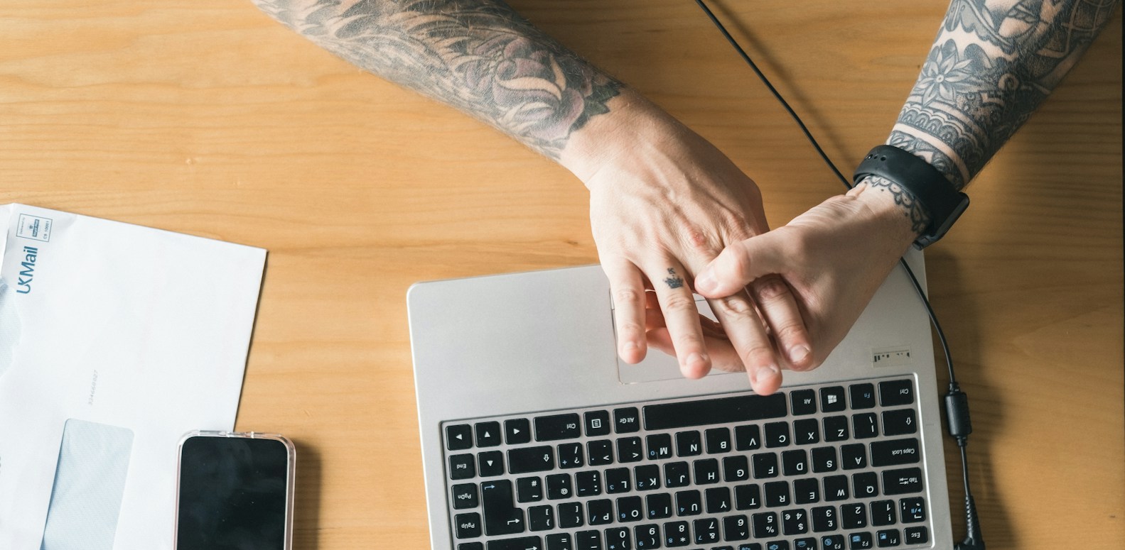 Personne travaillant sur un MacBook Pro posé sur une table en bois