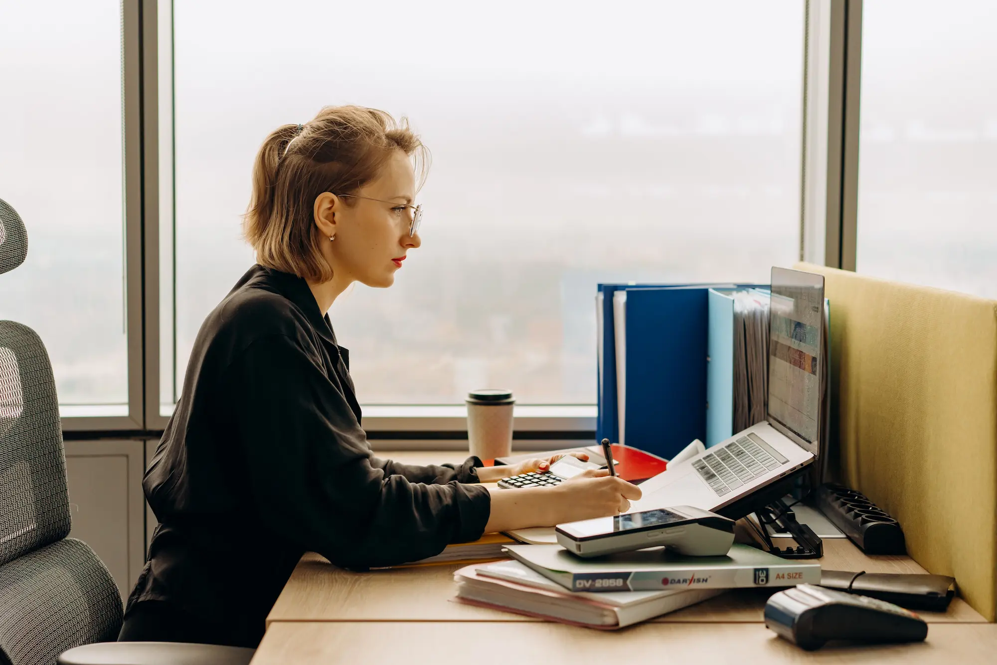 A credit analyst working at a desk by a window