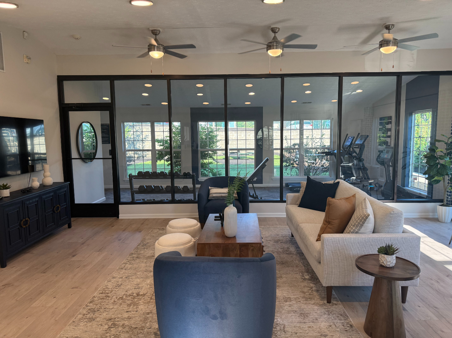 Community Lounge with sofa and tv and view of fitness center