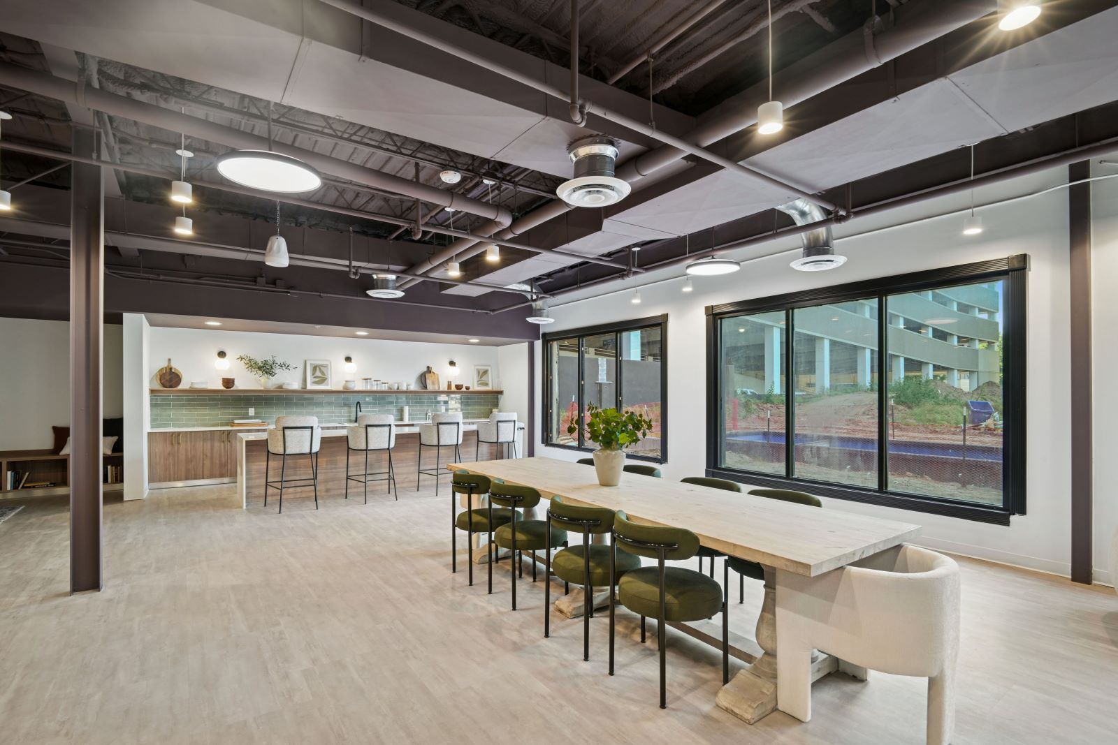 Modern community kitchen with a long bar and dining tables, offering a social space with an industrial design at The Pulse in Oklahoma City, Oklahoma.