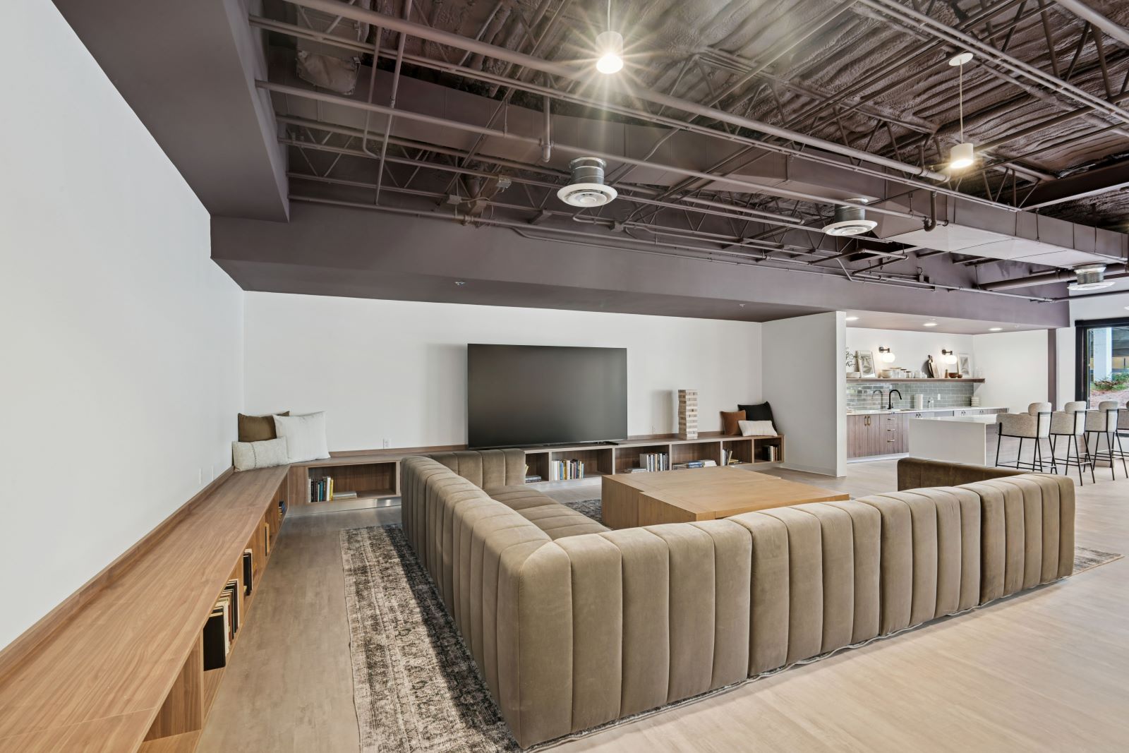 Stylish and modern clubhouse lounge with a large TV, comfortable sofas, and exposed industrial ceiling, a perfect place for residents to relax at The Pulse in Oklahoma City, Oklahoma.