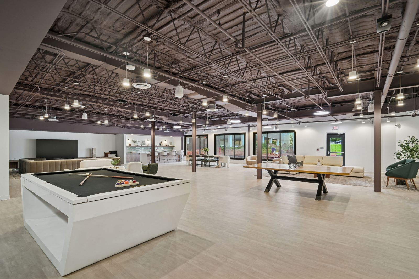 Expansive clubhouse with a billiards table, lounge seating, and an industrial-style ceiling, providing resident entertainment at The Pulse in Oklahoma City, Oklahoma.