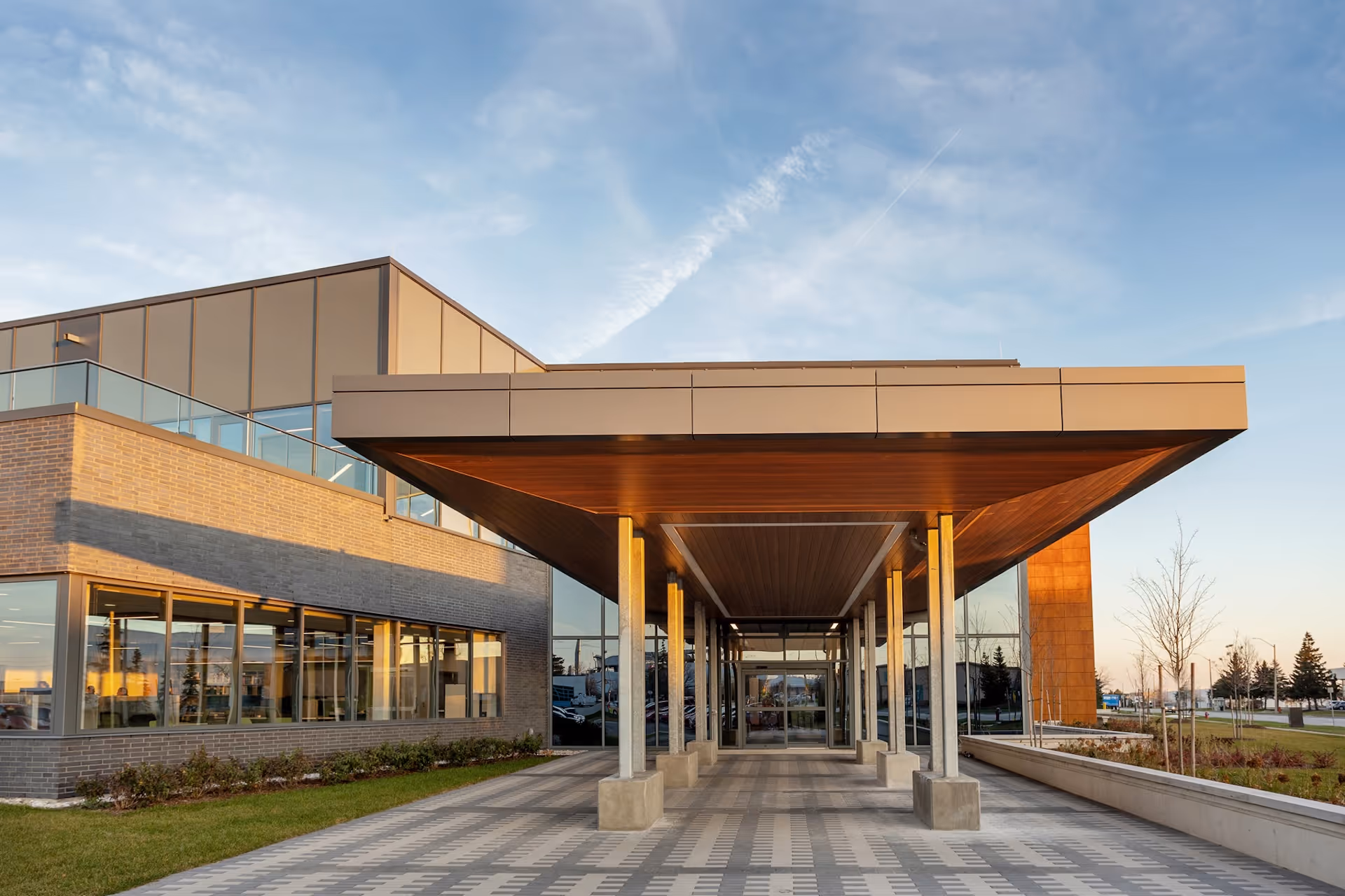 Exterior salter pilon designed building with glass walls, brick facade, and a wood-accented entrance canopy.