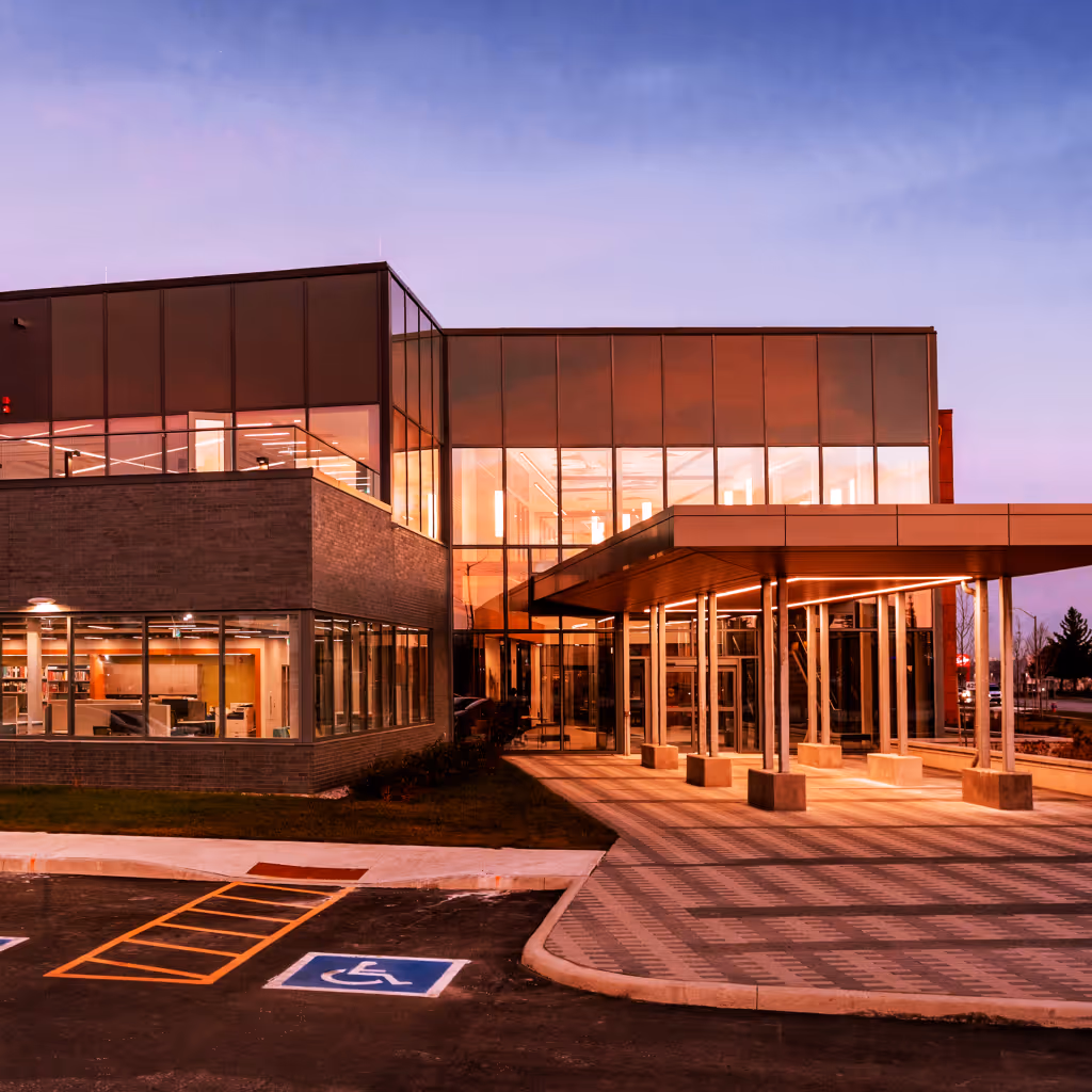 Exterior of Brampton Fire Headquarters at dusk, showcasing glass facades and illuminated entrance canopy designed by Salter Pilon Architects.
