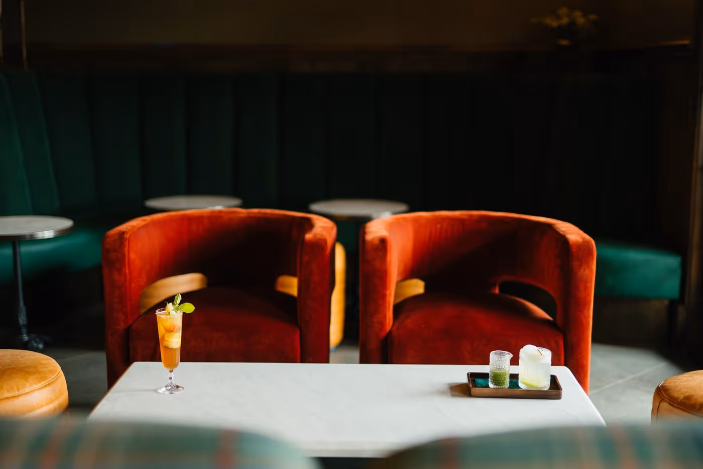 Interior of Stewart’s with red velvet chairs, marble table, cocktails, and upscale lounge atmosphere