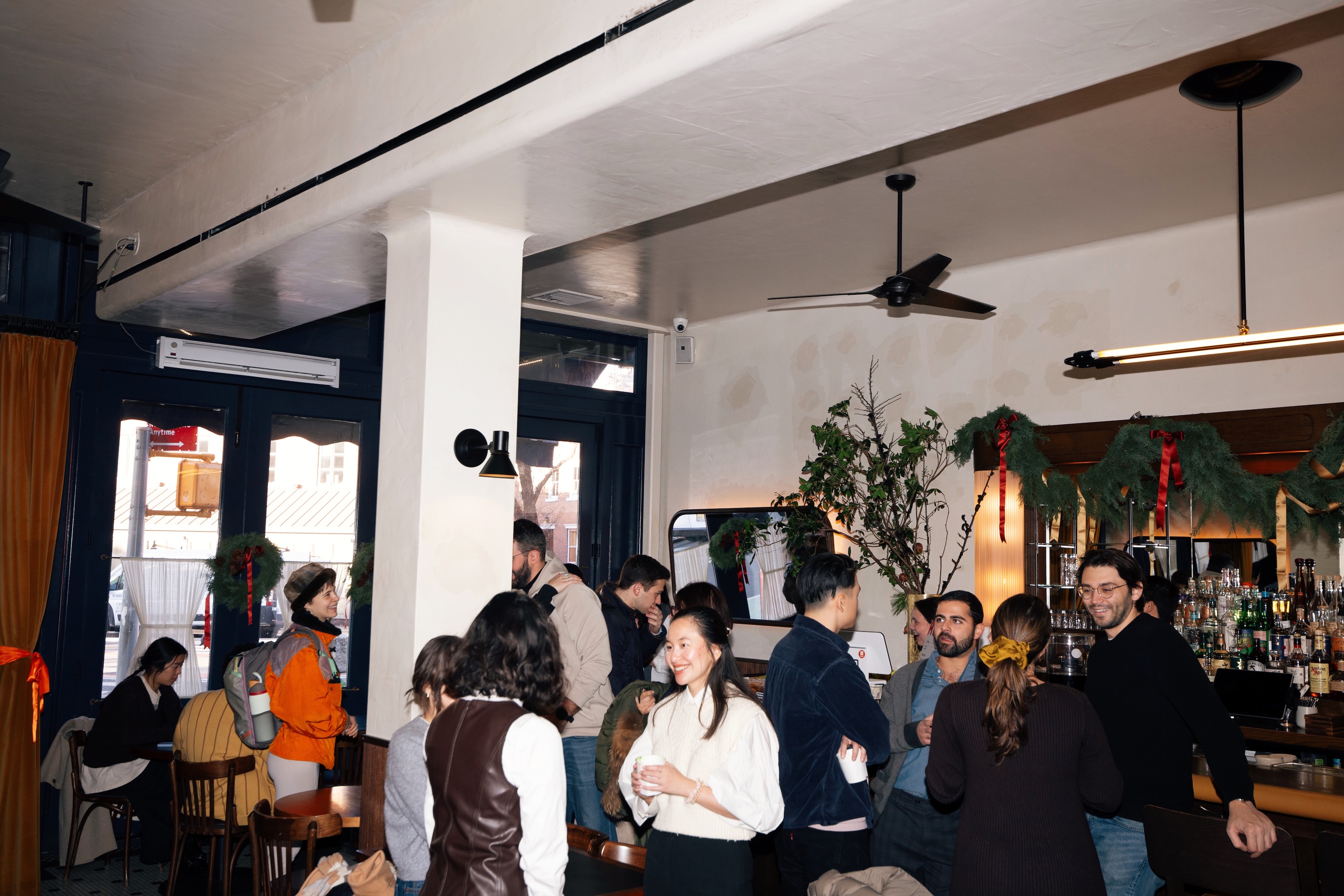 Group of people standing and talking inside a cozy cafe.