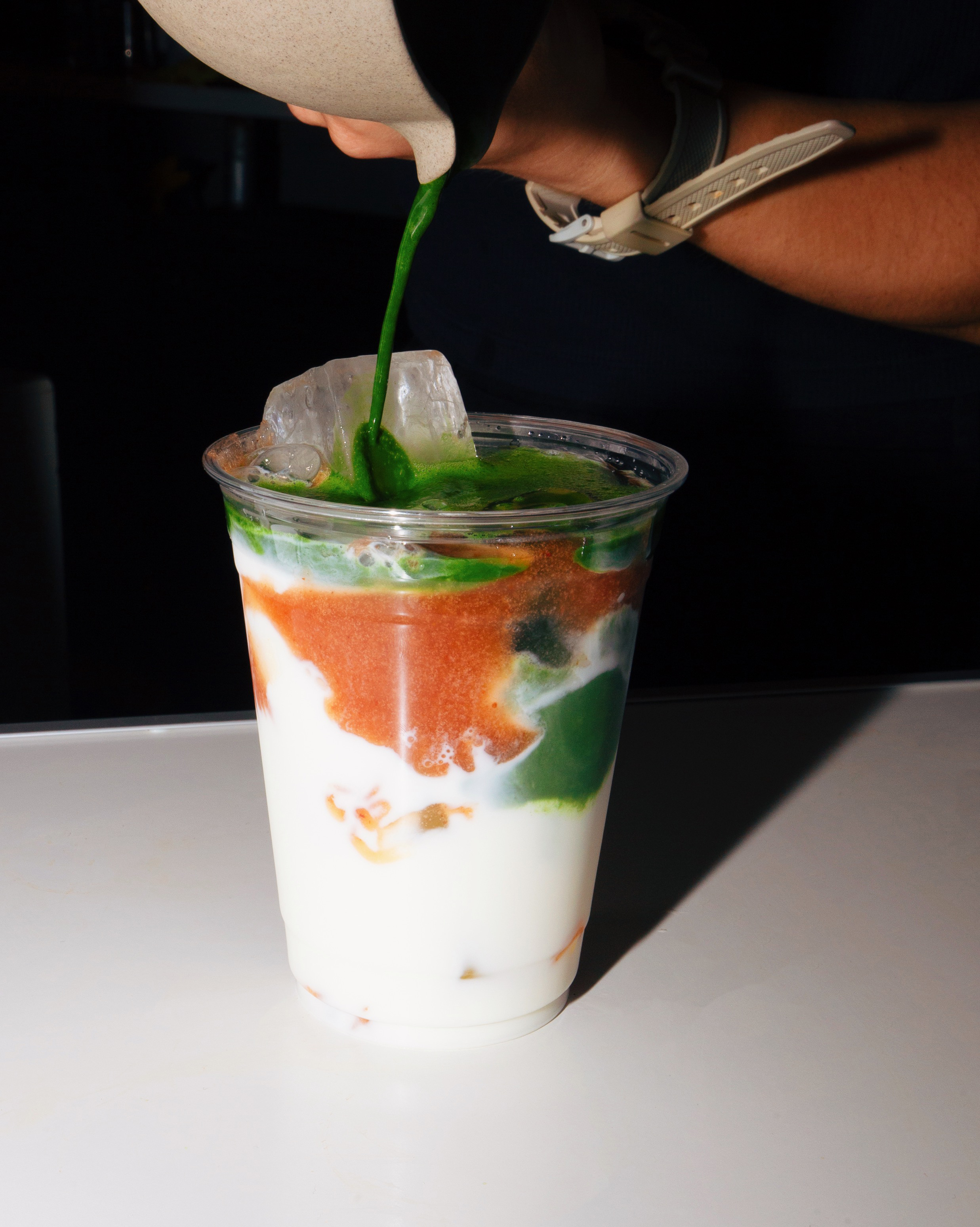 Matcha being poured over an iced latte
