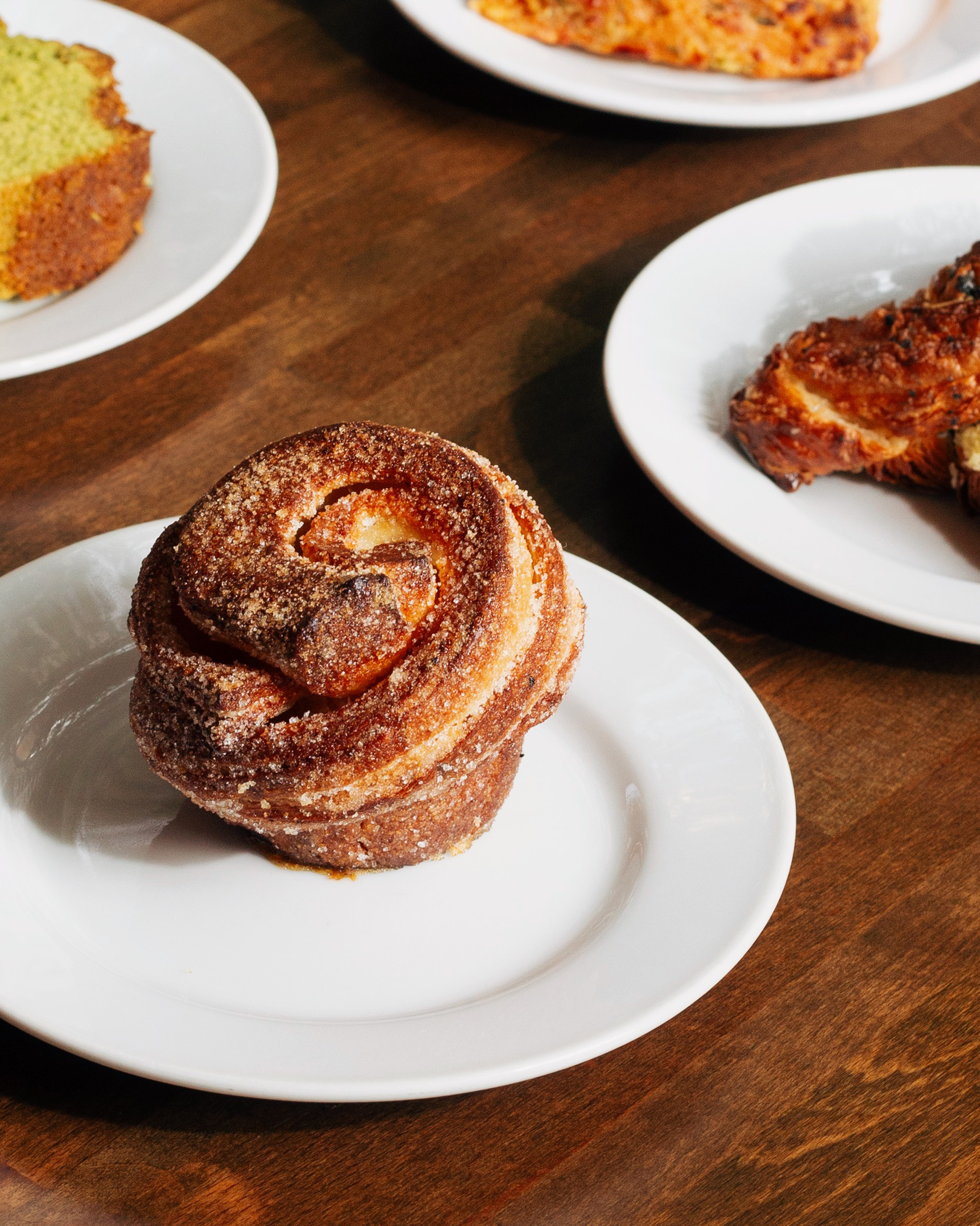 Sugar-dusted cruffin with matcha loaf and pastries on a wooden table