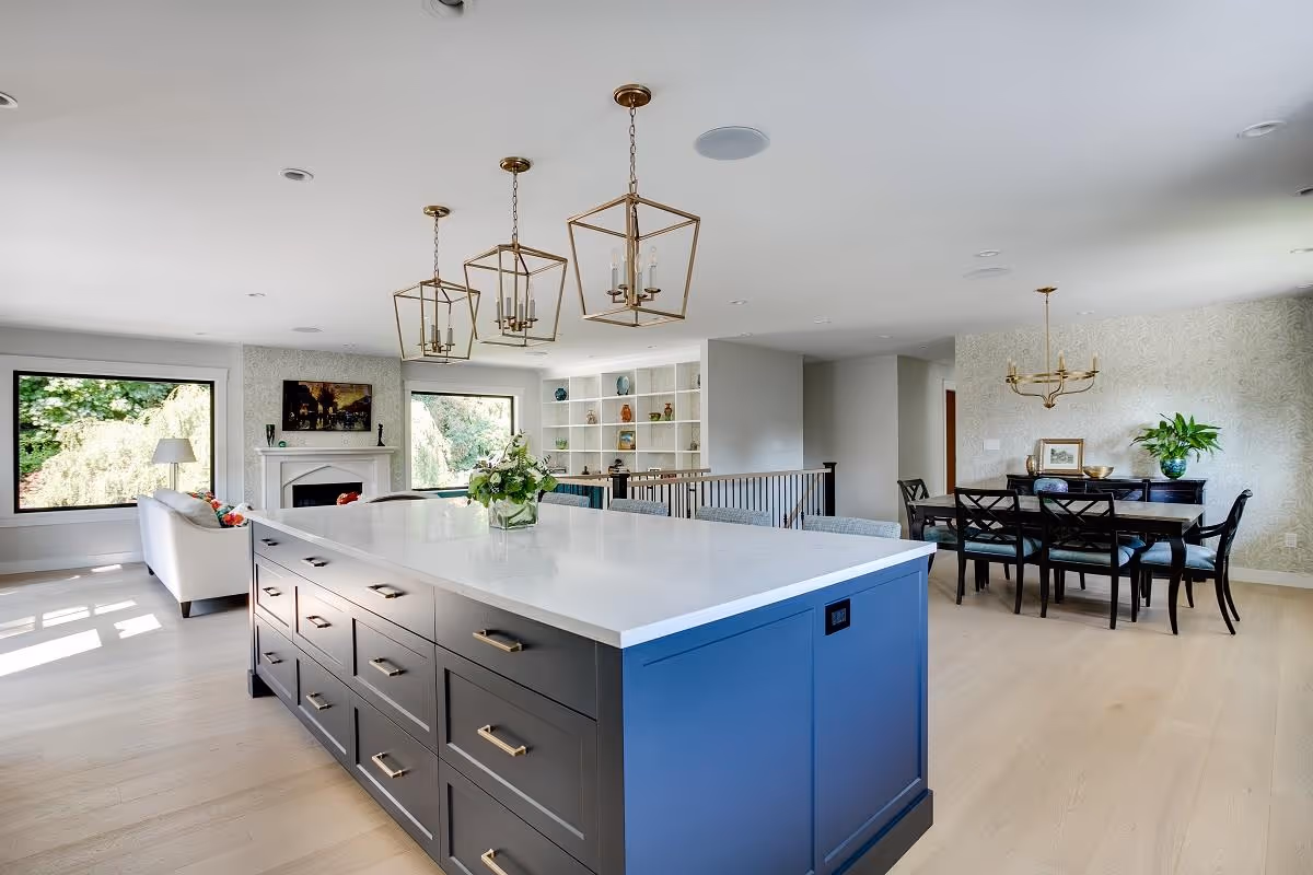 Modern open-concept kitchen with blue island, hanging lantern lights, and dining area