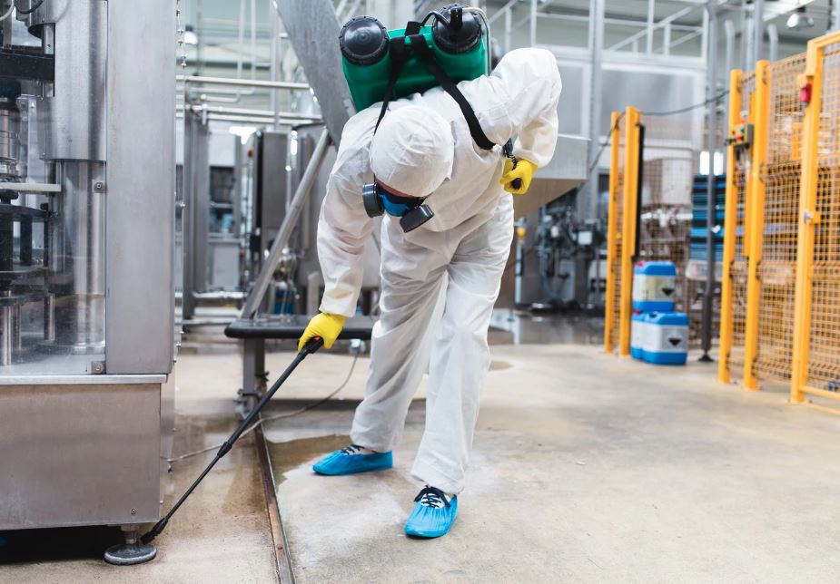 Worker spraying disinfectant in industrial area.
