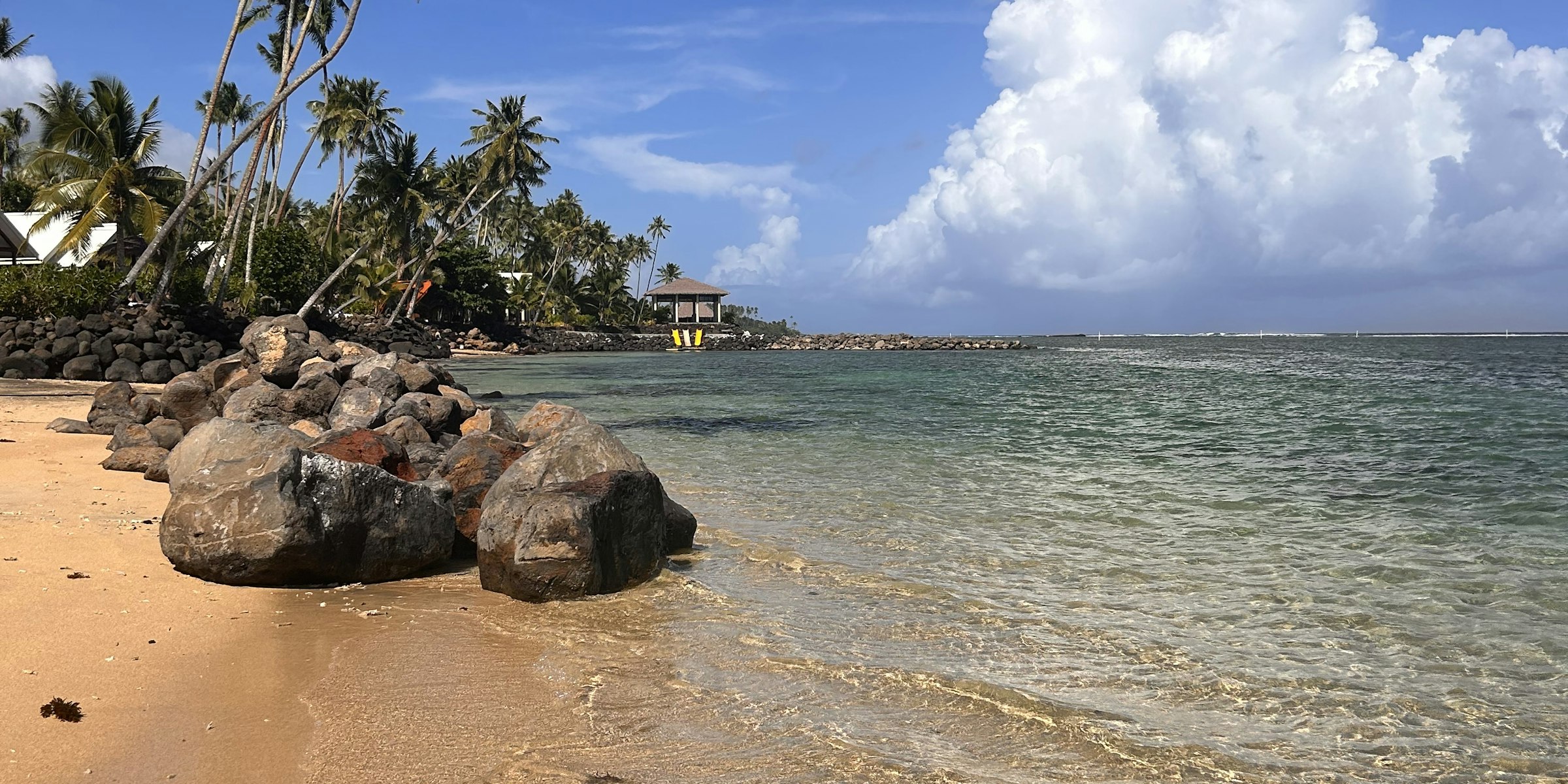 Sunny beach with rocks and palm trees in Samoa