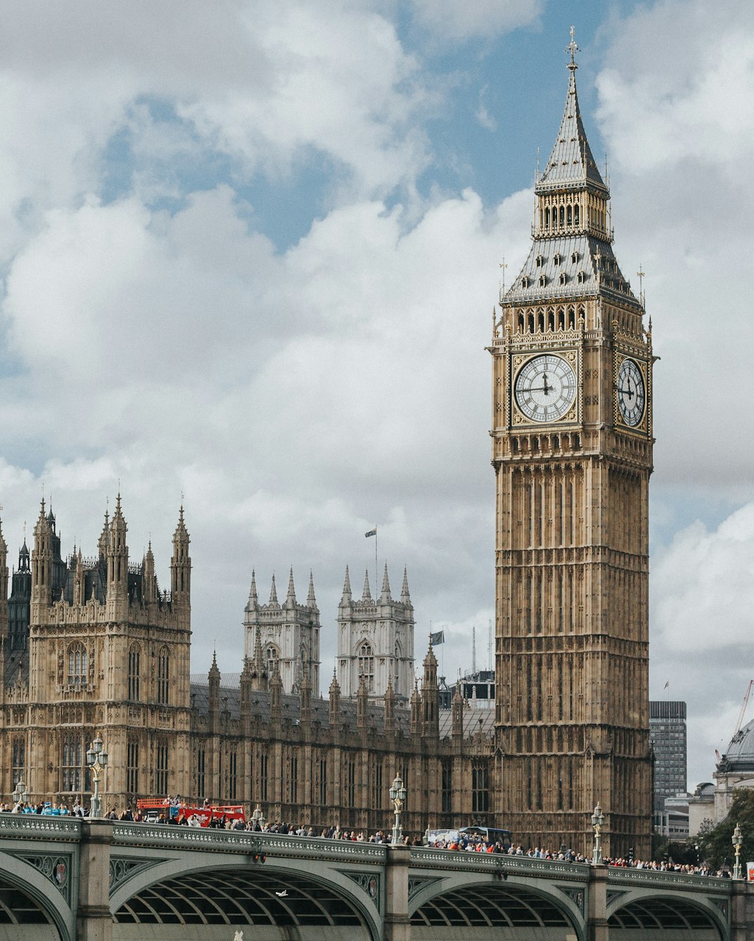 Big Ben and the Houses of Parliament beside Westminster Bridge in London on a partly cloudy day.