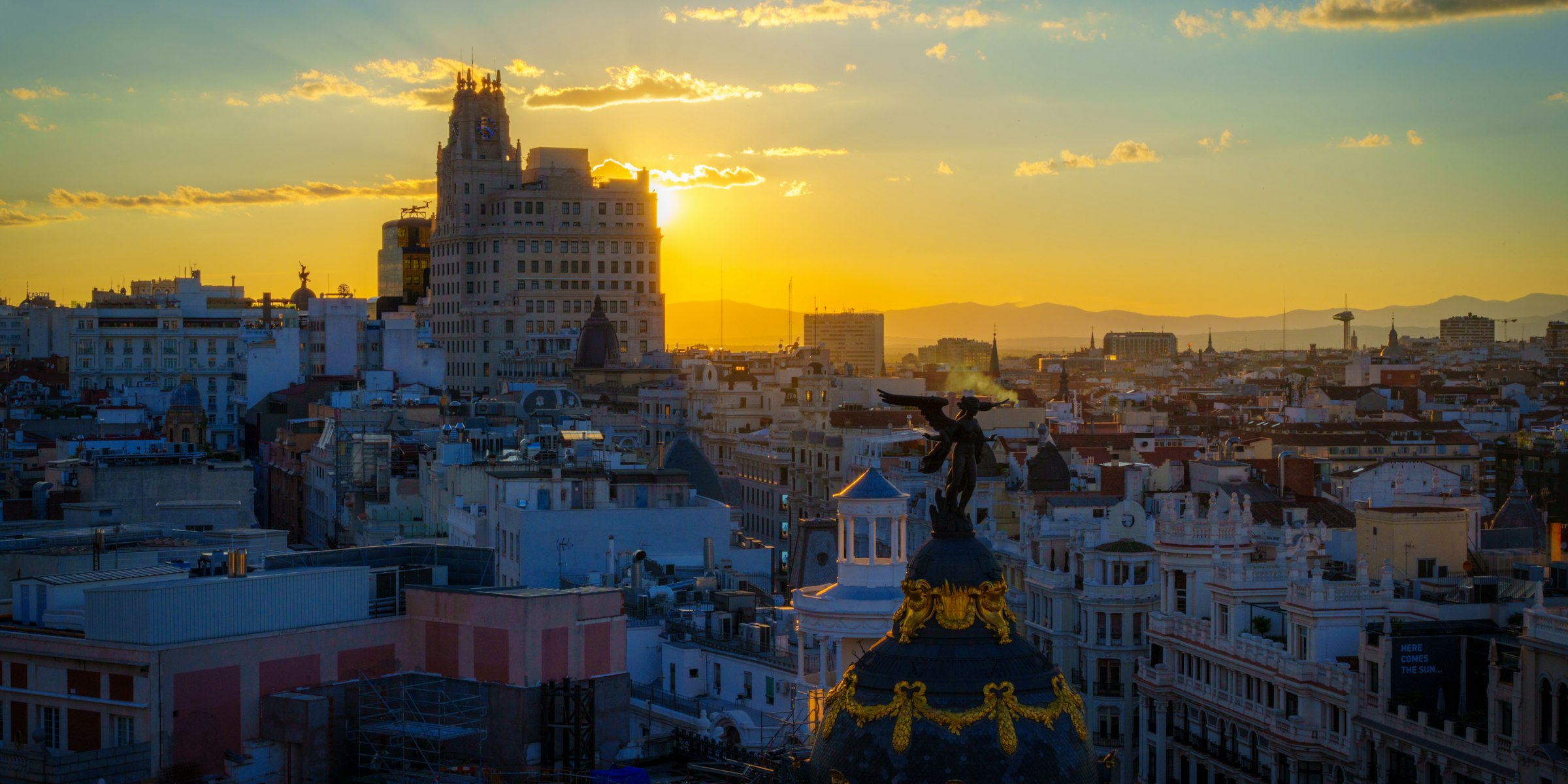 Sun setting over the Madrid skyline with the Metropolis building silhouetted in golden light