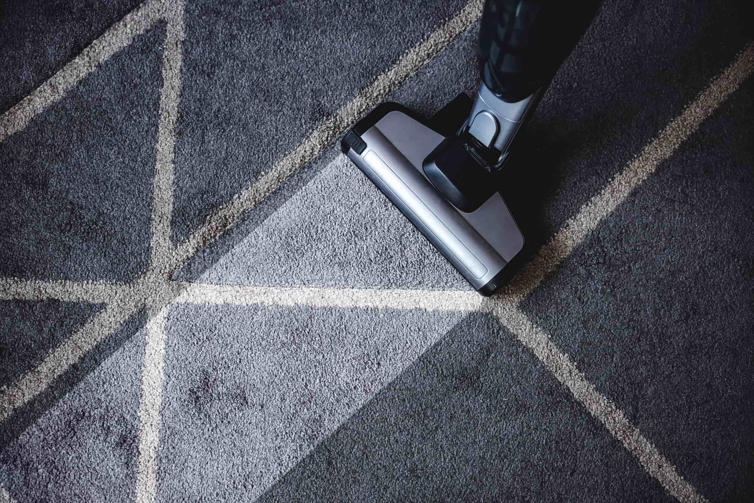 Vacuuming a patterned area rug to remove dirt during a deep cleaning process