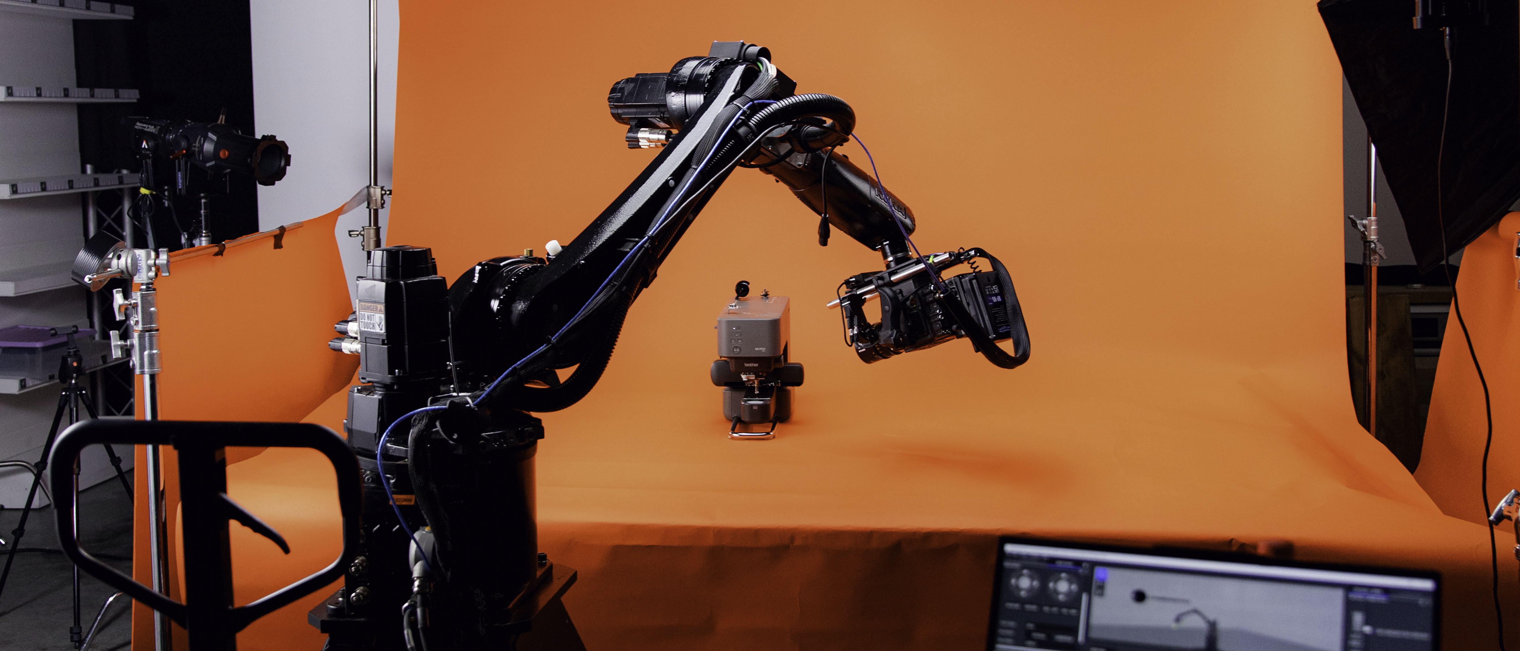 Behind-the-scenes photo on set filming for Brother Sewing. Cinebot/Robot arm can be seen in operation against a coloured backdrop in a studio.