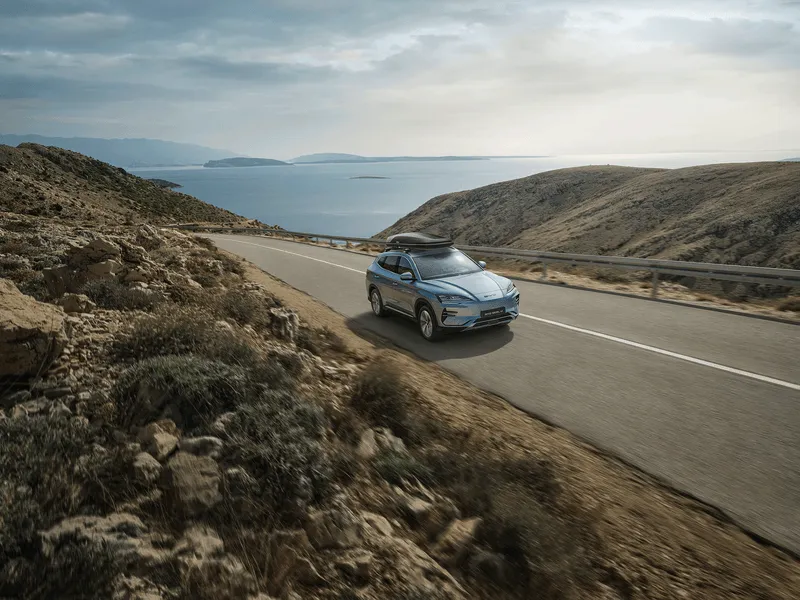 BYD SEAL U, Komplettansicht von Vorne, Dachbox, Fahrt auf Straße mit Meerblick