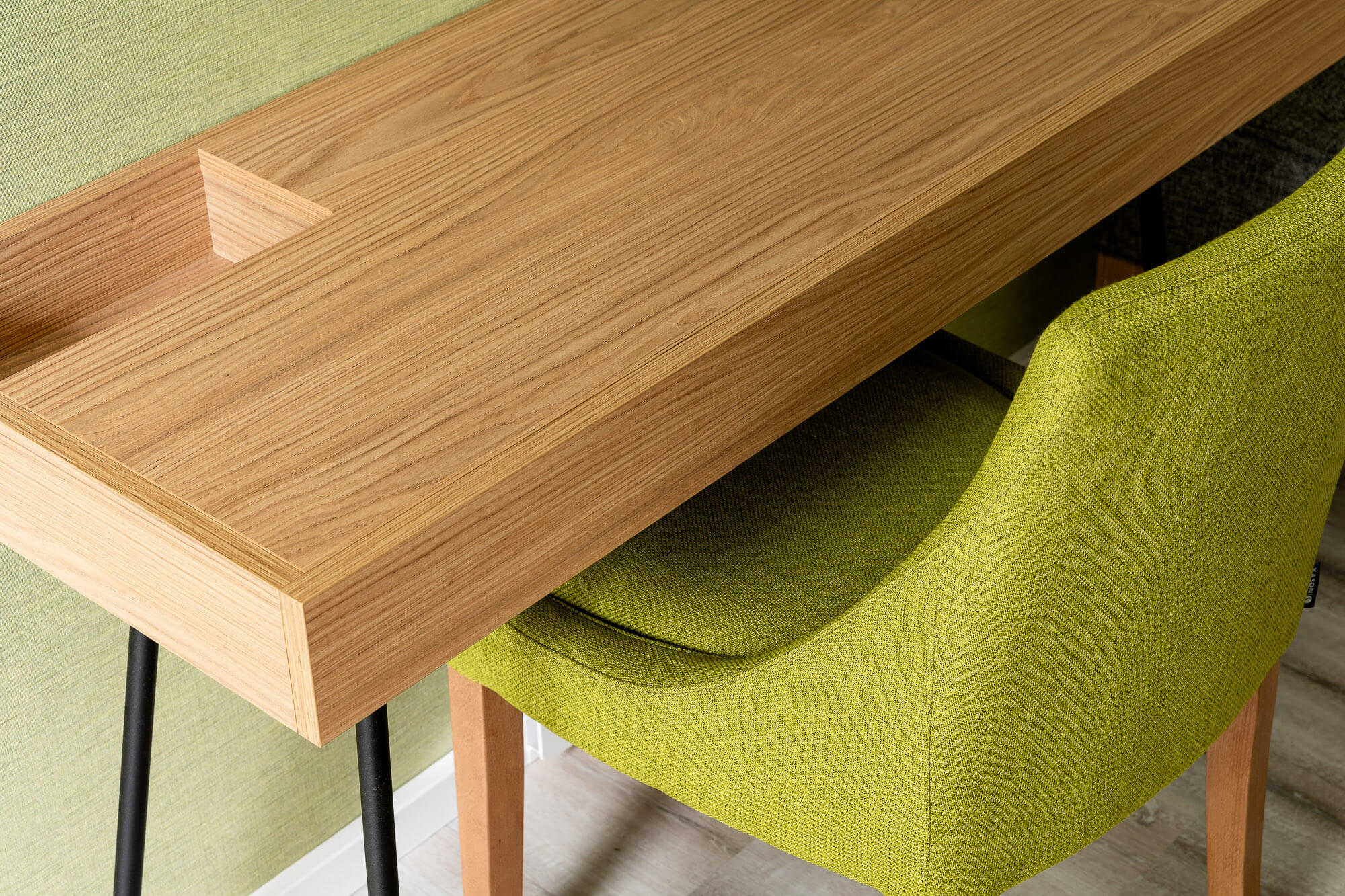 Holzschreibtisch mit grünem Stuhl im Hotelzimmer