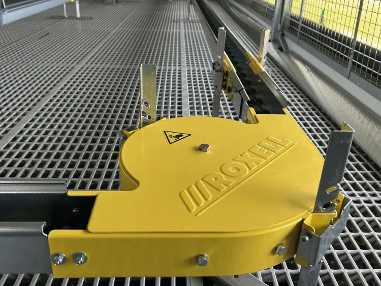 Yellow Roxell branded machine part on metal grating inside industrial cage.