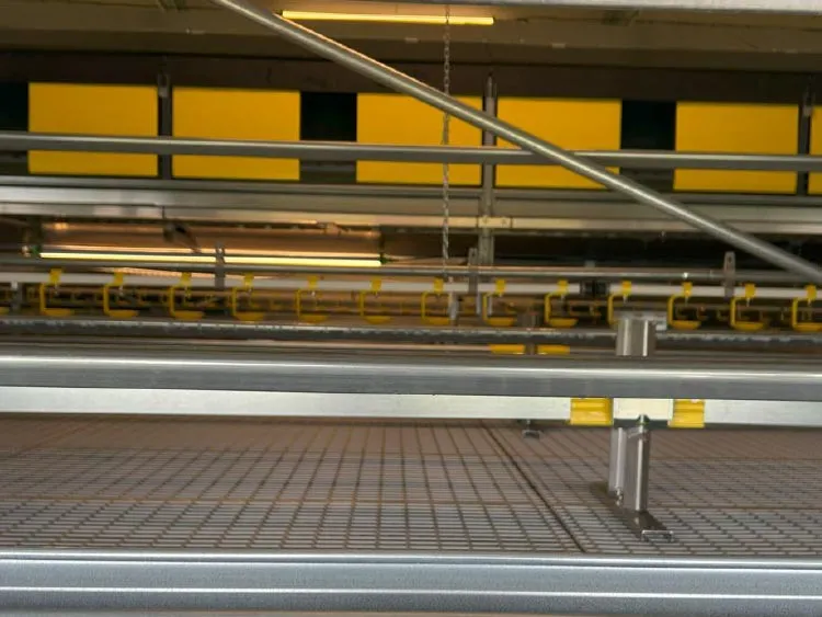 Industrial metal shelving with pipes and yellow brackets in a warehouse or factory setting.