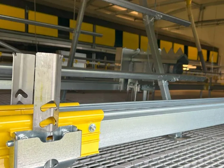 Close-up of metal and yellow structural rail components inside an industrial shed.
