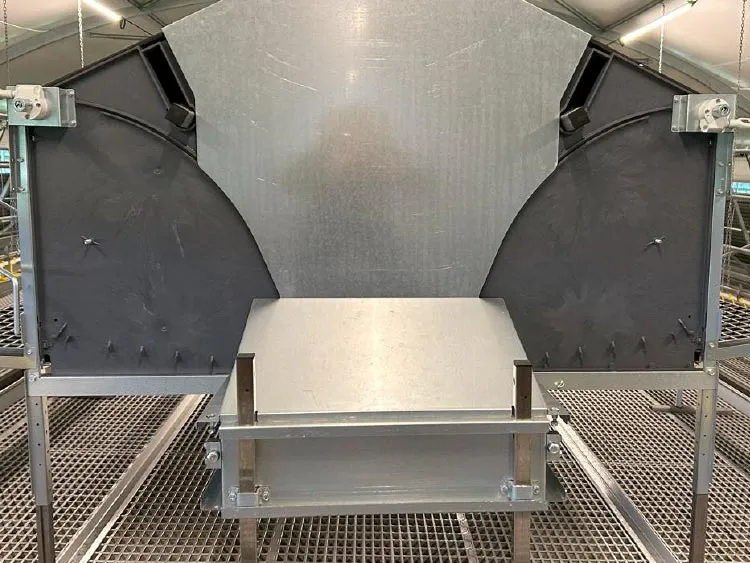 Metal industrial feeder with two black circular side panels inside a facility.