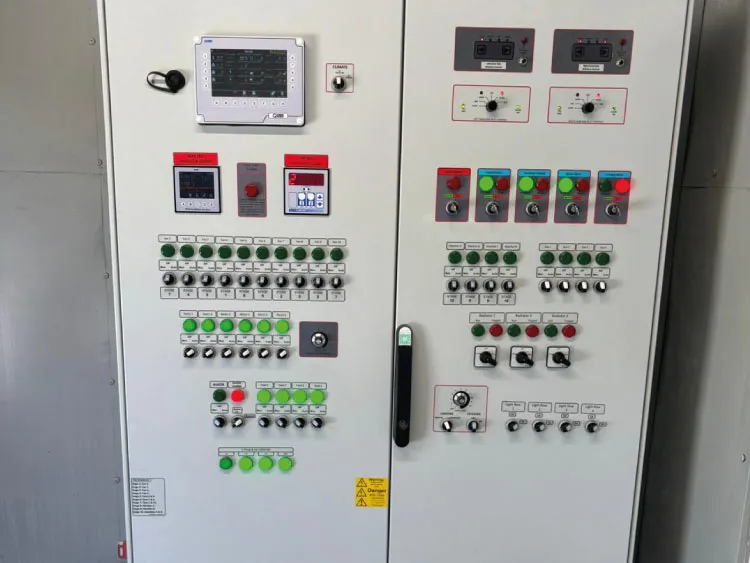 Industrial control panel with multiple buttons, switches, and digital displays on white cabinets.