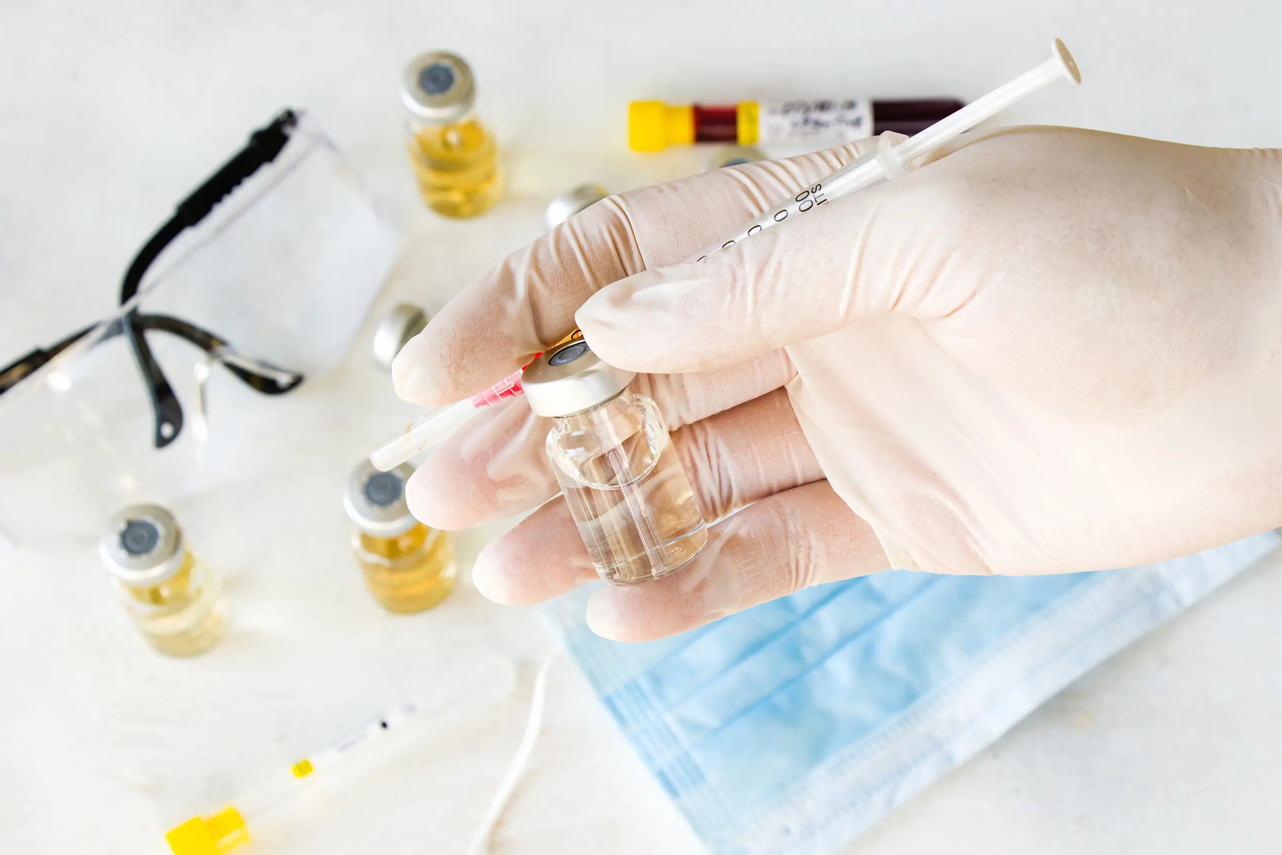 Doctor's hand holding a syringe and a bottle with liquid