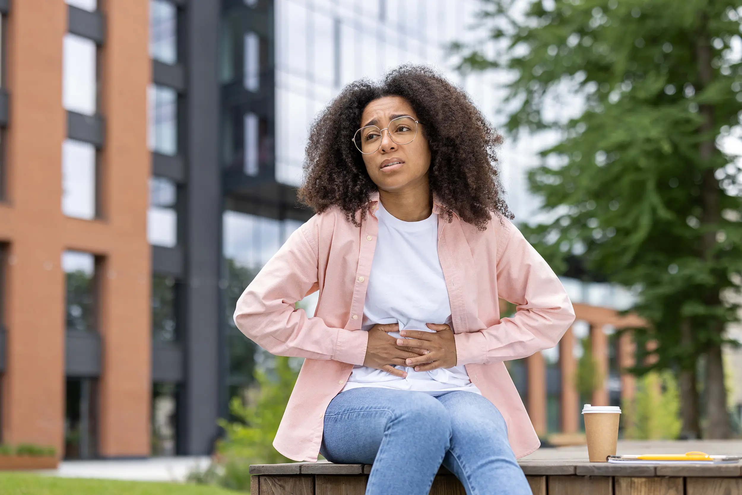 Female student experiencing gut issues in front of the university building