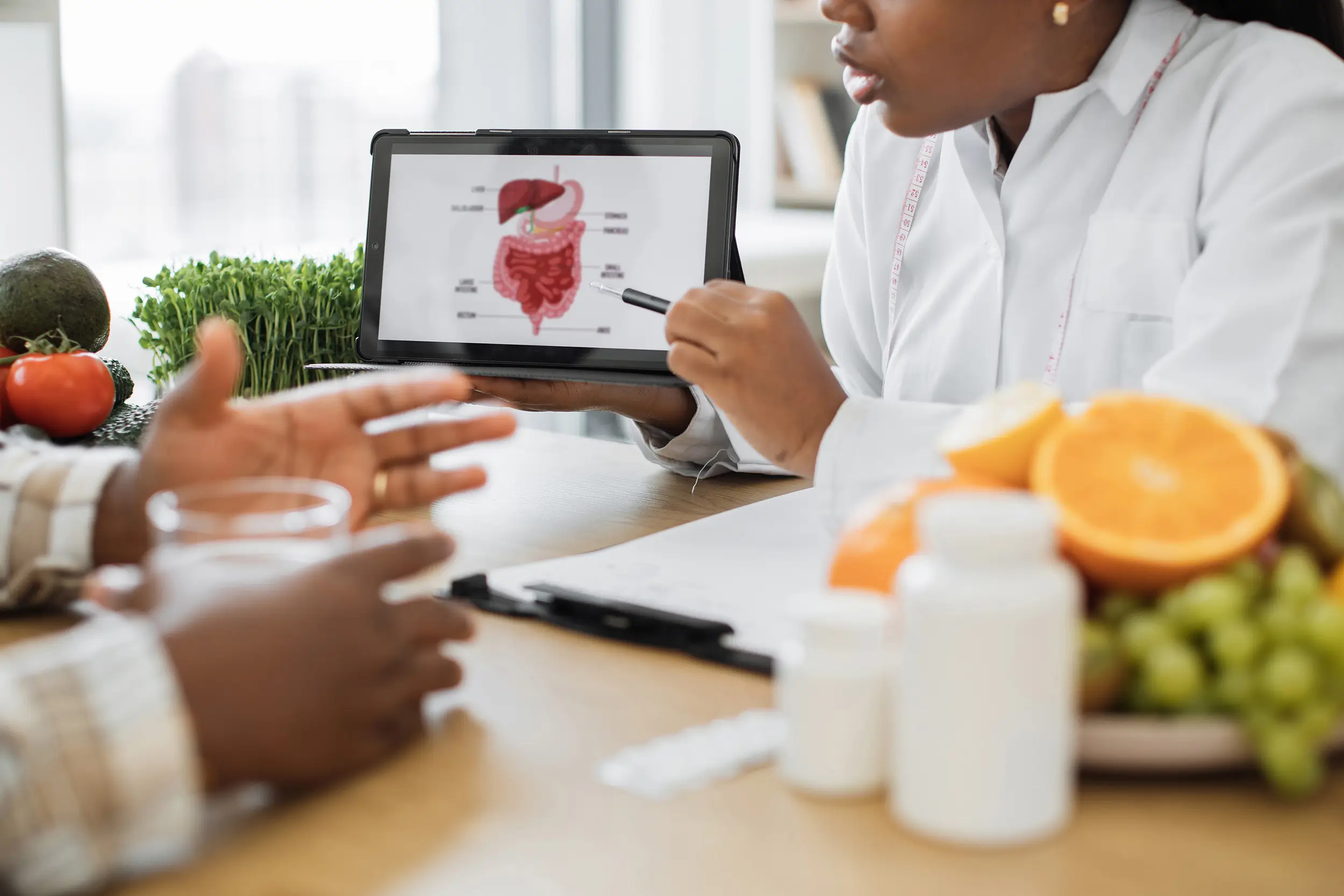 Nutritionist explaining diet to her patient with healthy food on her desk